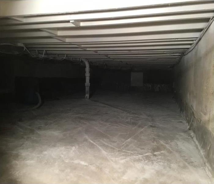 crawlspace with plastic sheeting on floor and clean wood framing
